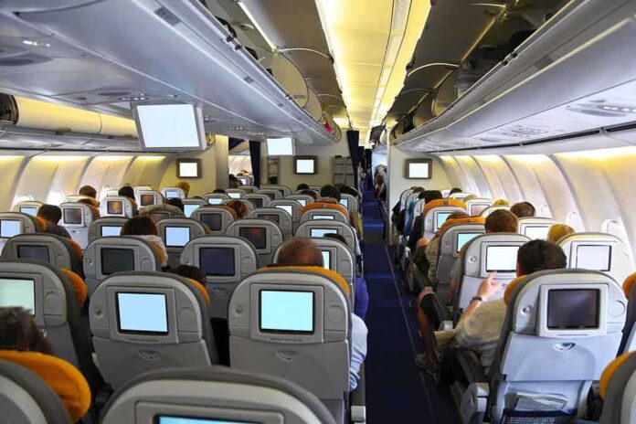 shutterstock_142431973.jpg Interior view of an airplane with passengers seated and using inflight entertainment screens