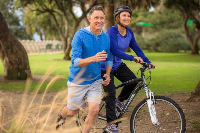 A couple enjoying outdoor exercise with one riding a bike and the other jogging alongside